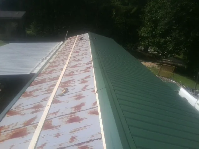 Old rusted panels beside newly installed green metal roofing — Wind Damage Roof Repair by Roofing Brothers in Haymarket