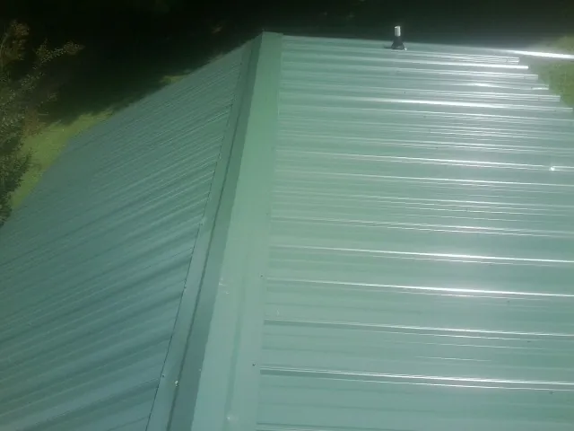 New green metal panels meeting at the ridge of a roof — Flat Roof Repair work by our crew in Haymarket