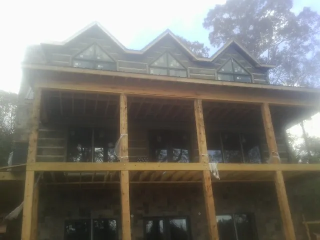 Dormers and porch framing on a large log home under construction — Roof Coating work by our crew in Haymarket