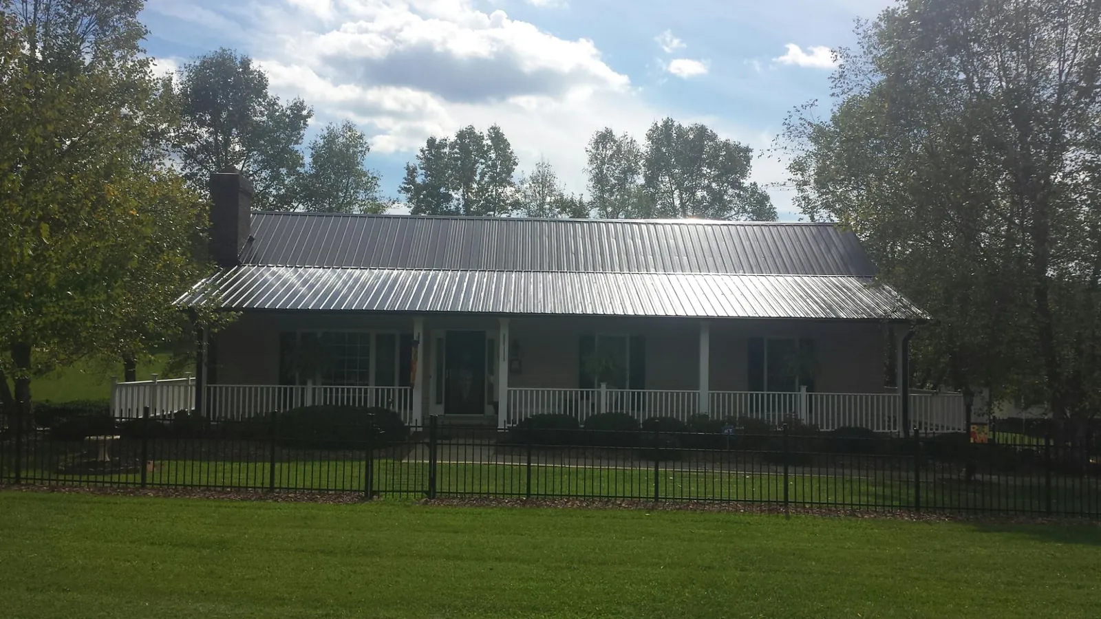 Gray metal roof on a brick ranch with a full width front porch — Gutter Guard Installation work by our crew in Haymarket