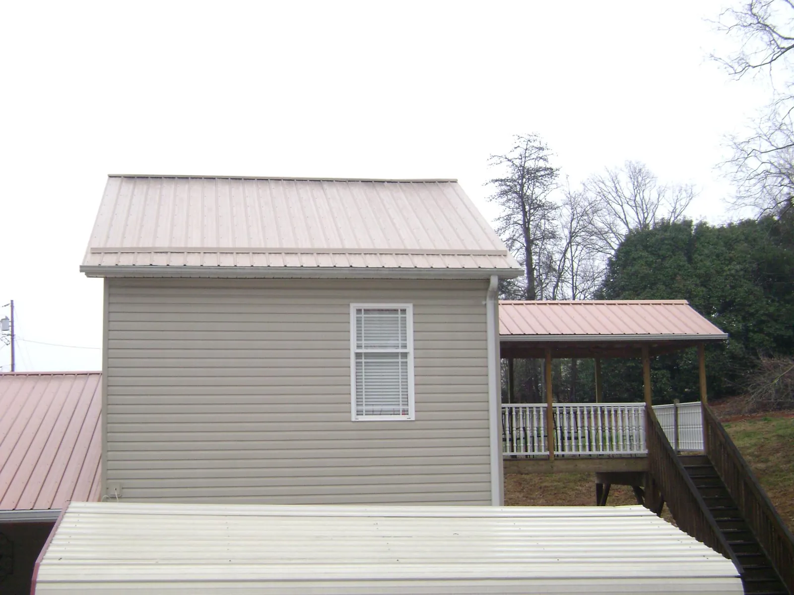 Tan metal roofs on a two story addition and attached porch, from a Roof Replacement job in Haymarket